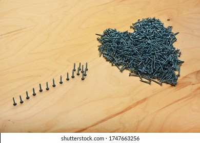 Heart and arrow symbols made of metal screws on a plywood sheet. Furniture manufacturing equipment and apartment repair tools.  Industrial veneer background.