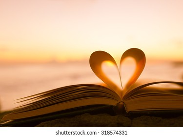Heart from a book page against a beautiful sunset. 