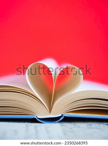 Heart from a book page on red background, book of love