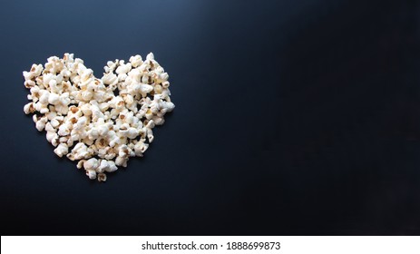 Heart of buttered popcorn on black background. View from the top. Copy space. Film and cinema concept