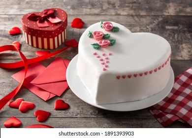 Torta de corazón para el Día de San Valentín, Día de la Madre o Cumpleaños, decorada con rosas y corazones de azúcar rosa en una mesa de madera