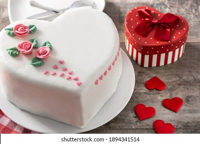 Torta de corazón para el Día de San Valentín, Día de la Madre o Cumpleaños, decorada con rosas y corazones de azúcar rosa en una mesa de madera.