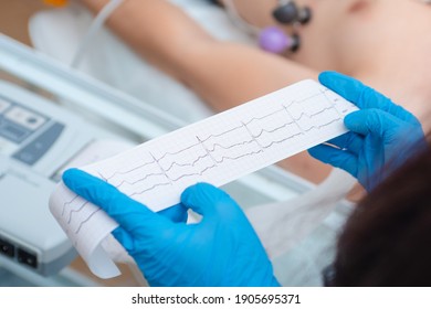 Heart cardiogram in the hands of a doctor close-up. Cardiologist is studying the testimony of an electrocardiograph.
