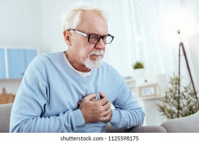 Heart Disease Symptoms. Attentive Senior Man Touching Chest And Wearing Glasses