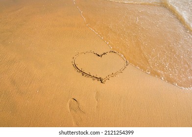 A Heart Drawn With Fingers On The Beach. The Waves Are About To Wash Over. Top View. Midday On The Pacific Coast. Valentine's Day. Romantic Concept.love Heart Shape.Lost Love Theme