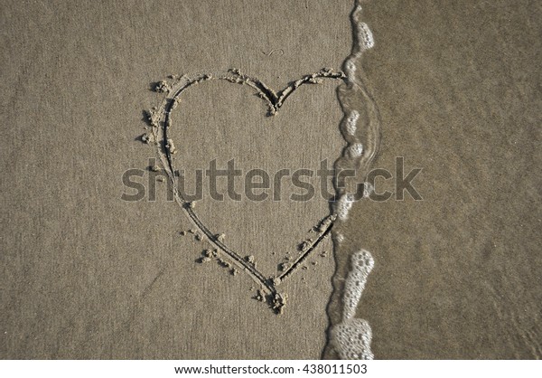 Heart drawn\
on the beach being washed away by\
wave