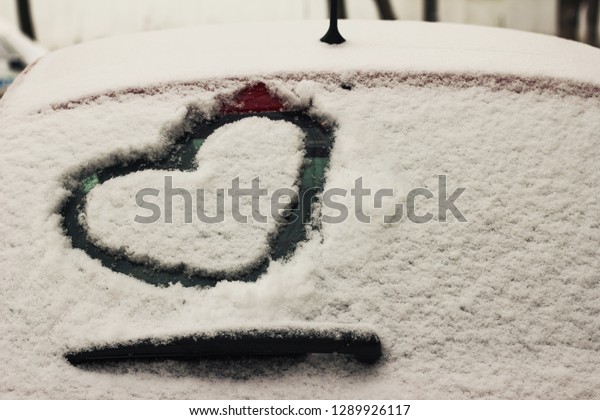 Heart\
drawn on a car windshield covered with fresh\
snow