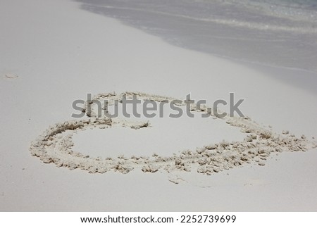 Heart drawn in the sand. Beach background. Love sign writing on sand. The Valentine's day tourism concept or background