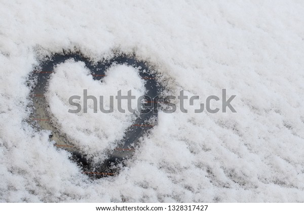 Heart drawn\
in the snow. Black heart on white\
snow.
