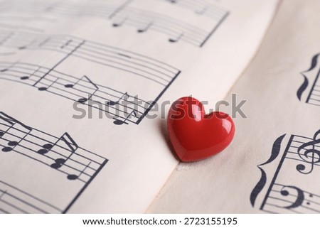 Heart figure on paper sheet with music notes, closeup