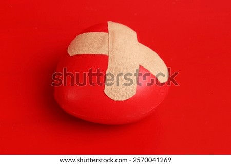 heart figurine with patch on red background. Concept of wounded love
