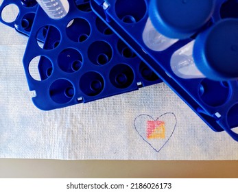 A Heart In Focus Among A Stack Of Test Tubes On A Lab Bench