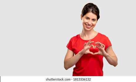 Heart Gesture. Send Love. Happy Woman In Red T-shirt Looking At Camera. Isolated On Neutral Copy Space. Affection And Desire. Romantic Emotion. Advertising Background