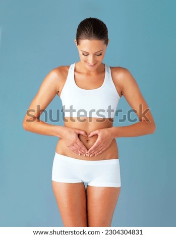 Heart, hands on abdomen and woman with gut health and wellness isolated on blue background. Weight loss, fitness and healthy female person with self love and body care in studio with diet