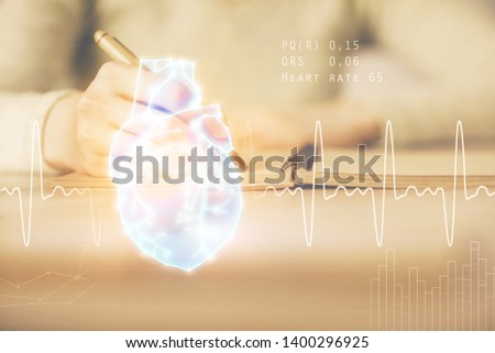 Heart hologram over woman's hands writing background. Concept of Medical education study. Double exposure