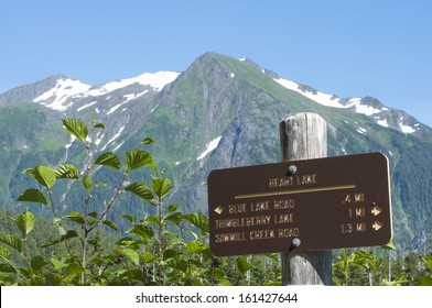 Heart Lake Trail Marker With Snow-capped Bear Mountain In Background Near Sitka, Alaska On Summer Day