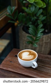 Heart latte art coffee on wood table background