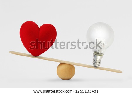 Heart and light bulb on scale - Concept of brain priority over heart in life