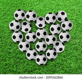 Heart Made Of Many Soccer Balls On Green Grass, Top View