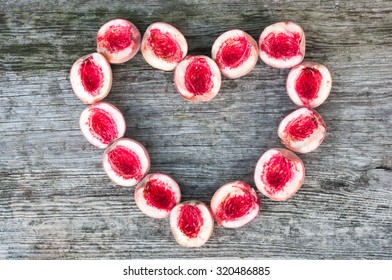 Heart made of Red peaches on a grey retro wooden background