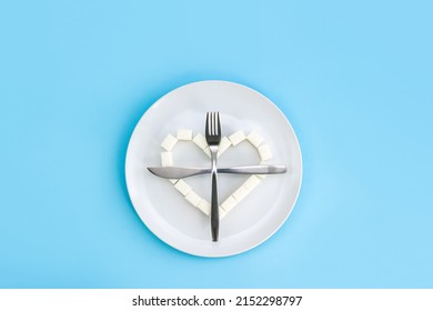 Heart Made Of Sugar Cubes On Plate And Crossed Fork And Knife. Refusal Of Unhealthy Food. The Danger Of Obesity Or Diabetes. Sugarfree Concept.