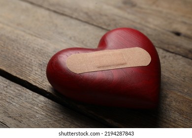 Heart With Medical Patch On Wooden Table, Closeup. Relationship Problems Concept