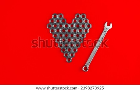 Heart from metal nuts and wrench on a red background 