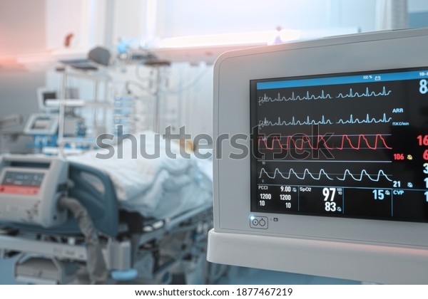 Heart monitor with ECG lines on the\
background of critical patient in the intensive care\
unit.