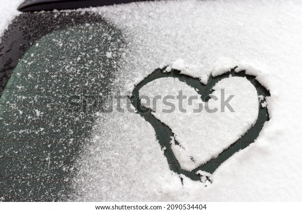 Heart on the car.Heart drawn\
on a car windshield covered with fresh Christmas snow in\
daylight.