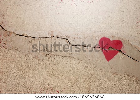 A heart painted on a cracked wall. The concept of broken heart, relationships, love, friendship, marriage, graffiti.