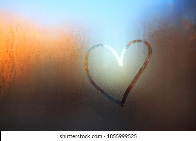 A heart painted on a fogged window.Heart on the fogged glass. Heart on the background of the window.The heart is a symbol of love drawn on glass - Shutterstock ID 1855999525