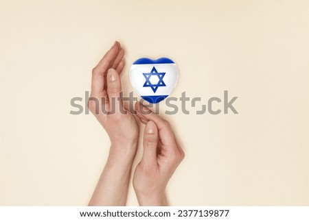 Heart with print of Israel flag in female hands. Flat lay. Copy space.