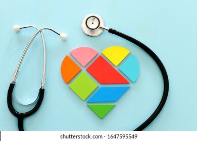 Heart puzzle and with stethoscope on blue pastel wooden background, medical concept