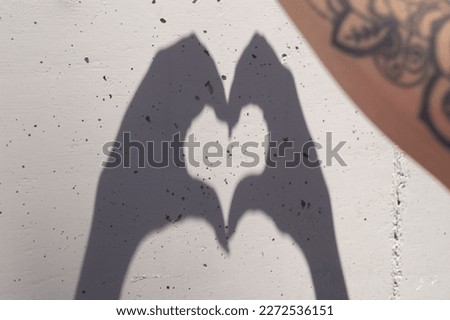 
heart shadow on the wall made by the hands of a woman