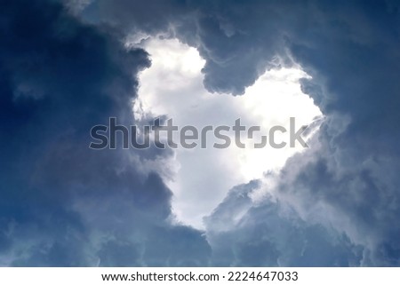 Heart shape appears in the cloudy dramatic sky. Heart frame shaped clouds on sky background.