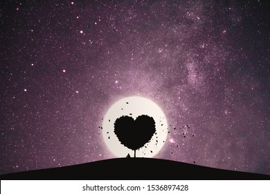 Heart shape of big tree and alone man sitting on a mountain under love tree landscape with fantasy night sky and full moon. Stunning views at lonely nights.