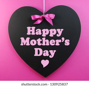 Heart shape blackboard with pink ribbon on pink background with Happy Mothers Day message. - Powered by Shutterstock