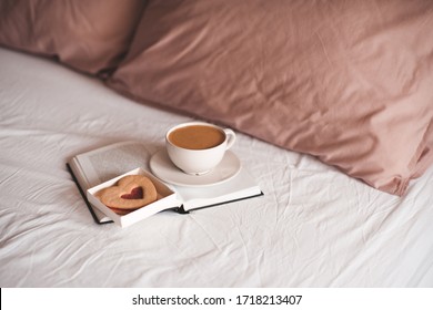 Heart shape cake with tasty fresh coffee in white cup in bed closeup. Good morning. Breakfast.  - Shutterstock ID 1718213407