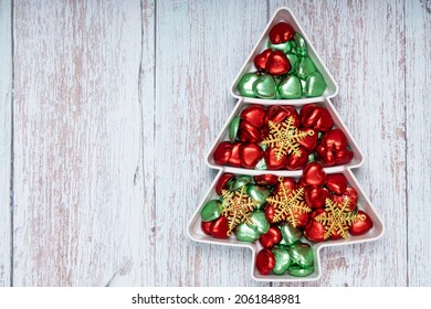 Heart shape chocolate candies and gold Christmas ornaments on a pine shape plate. - Powered by Shutterstock