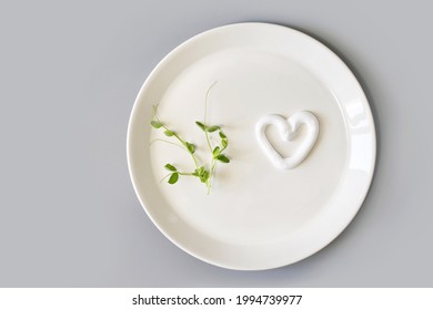 Heart Shape Cream. Beauty Lotion. Mayonnaise Smear On White Plate. Top View With Copyspace. White Product Smear. Valentine Concept. Green Peas. Grey Background