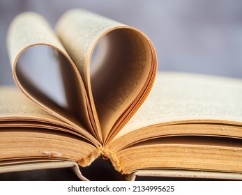 The Heart Shape Created By The Open Yellowed Pages Of An Old Hardcover Book, Soft Focus, Shallow Depth Of Field.  I Love Reading! Educational Topics. No People.