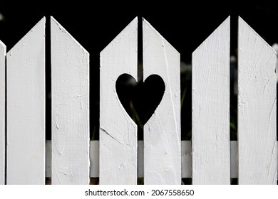 Heart Shape Cut Out Of White Picket Fence Outside Residential Home In The Suburbs