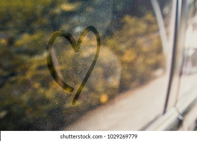 Heart shape drawn on the side window of the parking car. 