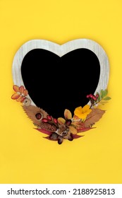 Heart Shape Frame For Autumn, Thanksgiving, Harvest Festival. Abstract Nature Concept With Leaves, Flowers,  Nuts. Minimal Fall Composition With Natural Flora. On Yellow Background. Flat Lay.