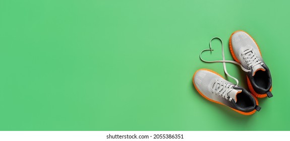 Heart shape shoe lace symbol gray textile sneakers over grassy green background. Active lifestyle, fitness and sport wide banner mockup with copy space. Shoelace heart of stylish mesh sport shoes. - Powered by Shutterstock