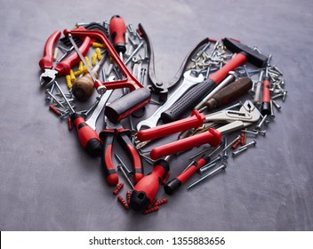 Heart Shaped Arrangement Of Assorted Red Hand Tools For Woodworking On A Textured Grey Background In A Close Up View