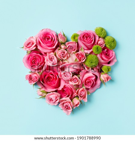 Heart shaped bouquet of beautiful fresh pink rose flowers on pastel blue background. Minimal Valentines Day, Easter, wedding or Mother's day concept. Creative spring or summer floral layout. Flat lay.