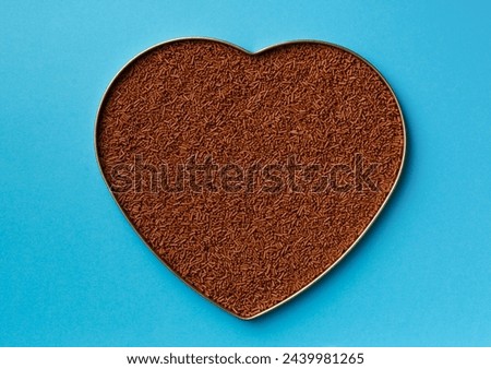 Heart shaped chocolate on a blue background top view with place for text. Chocolate chips in a box in the shape of a heart on a blue background. Valentine's Day. Dark chocolate on a blue background