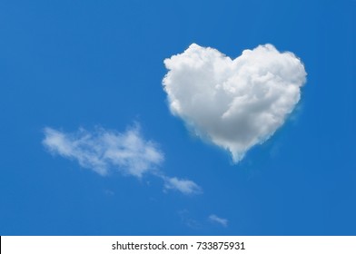 Heart shaped cloud on bright blue sky and white clouds.