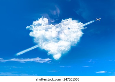 Heart shaped clouds in blue sky with plane